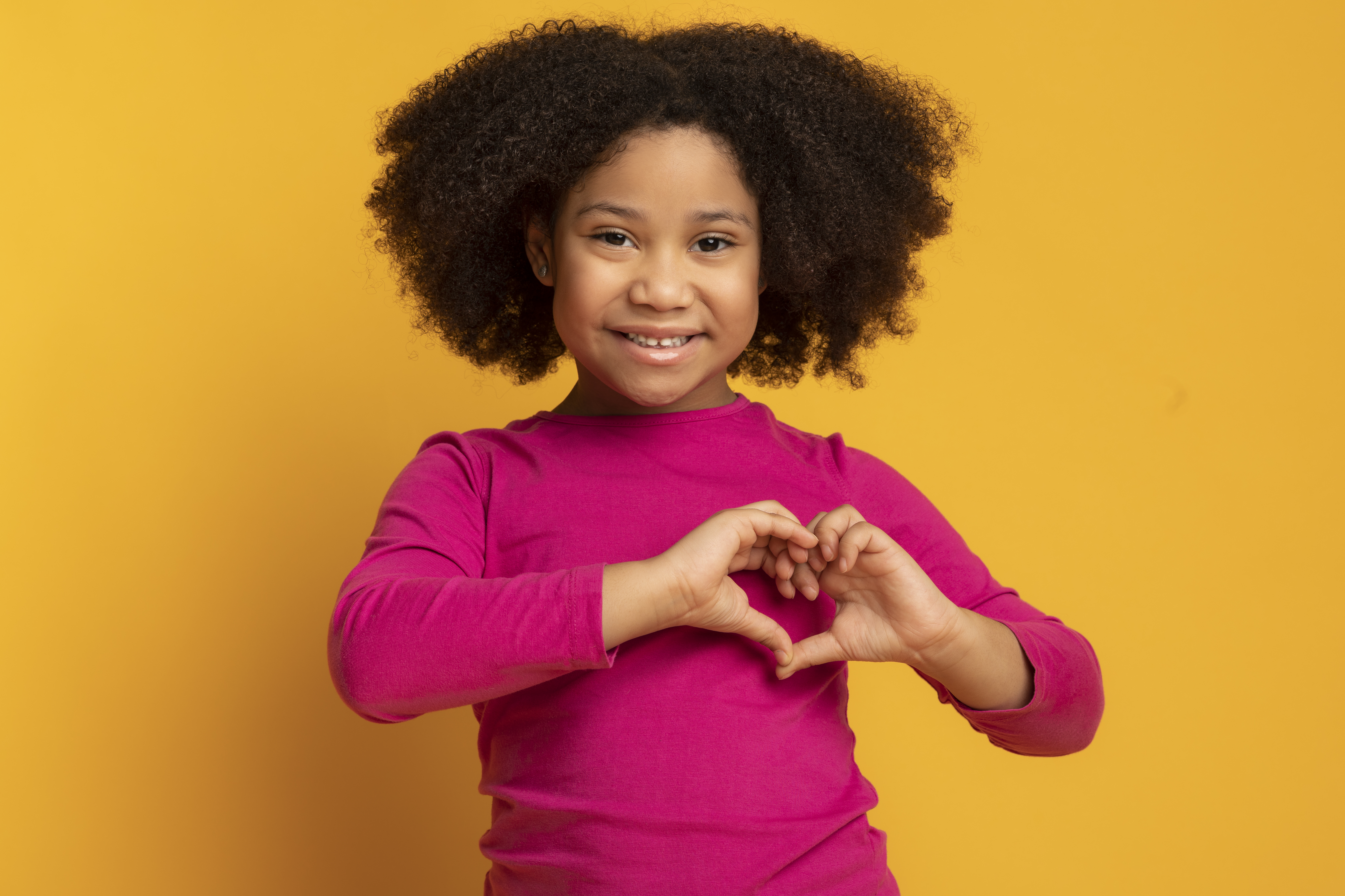 girl making a heart shape with her hands