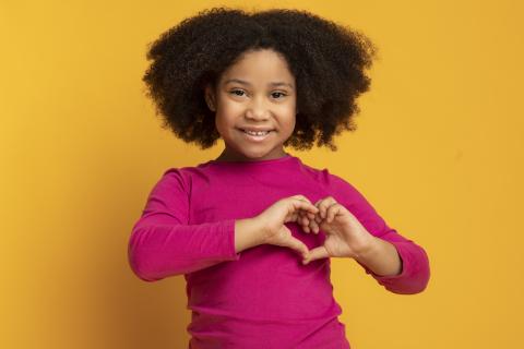 girl making a heart shape with her hands