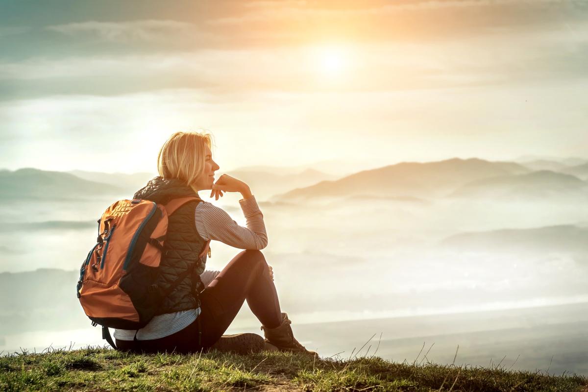 Woman sitting on mountain overlook with mountain view in background